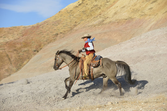 USA, Wyoming, cowgirl riding in badlands