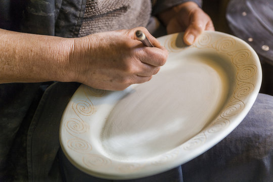 Potter in workshop engraving a plate