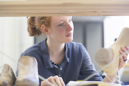 Female shoemaker looking at last