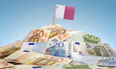 Flag of Malta sticking in a pile of various european banknotes.(