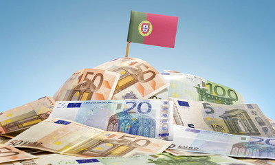Flag of Portugal sticking in a pile of various european banknote