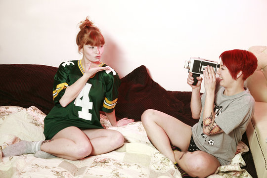 Woman filming her female friend with super mm camera at home
