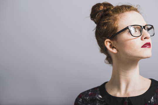 Young woman with glasses and bun looking up