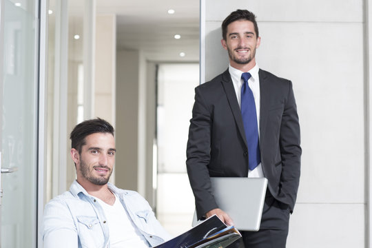 Casually and formally dressed twin males in office