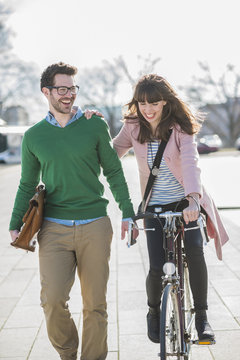 Happy couple going home together, woman riding bicycle