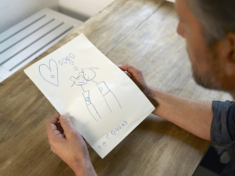 Mature man looking at child's drawing