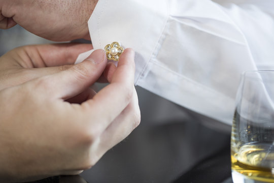 Best man closing cufflink at groom's shirt