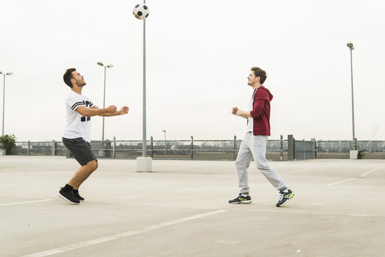 Two young men playing soccer on parking level