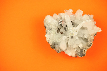 Picture of a whole piece of white quartz crystal formation with irregular texture, shot on orange...