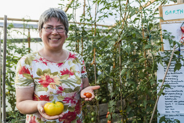 Woman in greenhouse holding red and yellow tomato