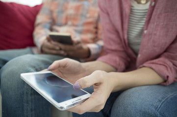 Men and women are looking at smart phone on the sofa