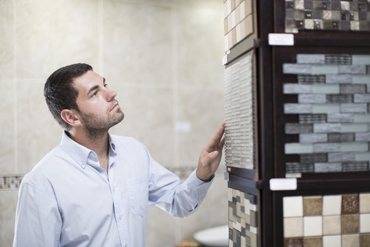 Man Looking At Tile Samples In A Bathroom Shop