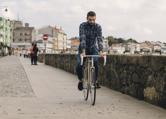Spain, Galicia, Ares, hipster man riding with a fixie bike