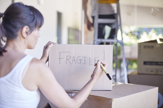 Couple moving house, woman writing on box