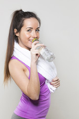 portrait of a sexy young athletic woman with towel around her neck drinking water for hydration after gym exercise