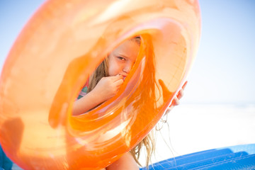 Girl on beach inflating an orange floating tire