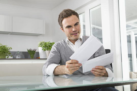 Man sitting in kitchen with letters