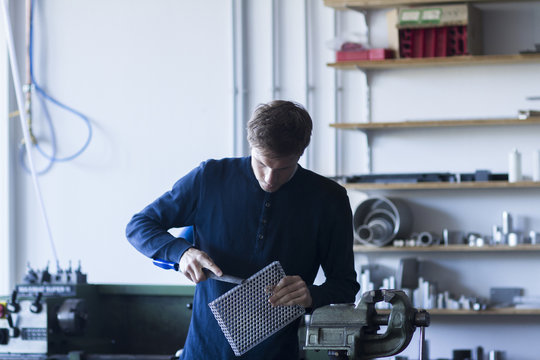 Technician in workshop working on piece of metal