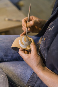 Potter in workshop painting a bowl