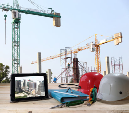 file of safety helmet and safety glasses on wood table in front of building construction background