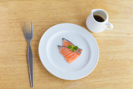 salmon in white dish and fork on wooden