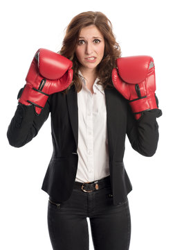 Businessfrau mit Boxhandschuhen schaut ängstlich