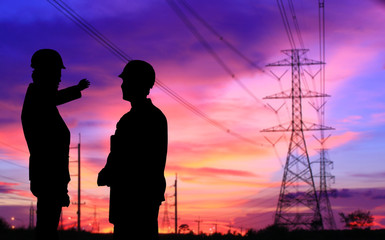 silhouette of two engineers standing at electricity station, discussing plan