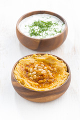 yoghurt sauce and hummus in bowls on white wooden table