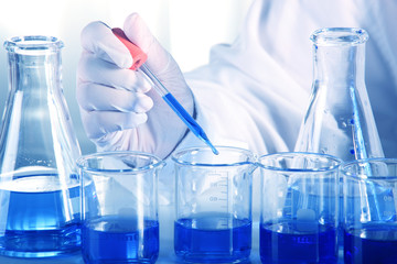 Flask in scientist hand with dropping liquid to test tube
