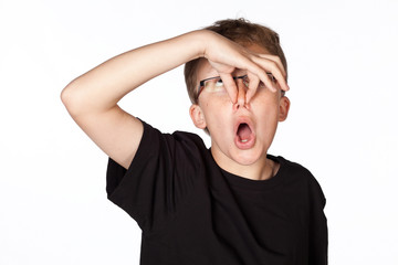 Funny shot of a boy holding his nose isolated on white.