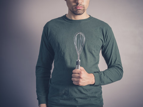 Young man holding a balloon whisk