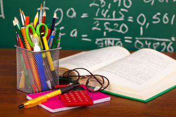 Back to school - blackboard with pencil-box and school equipment on table
