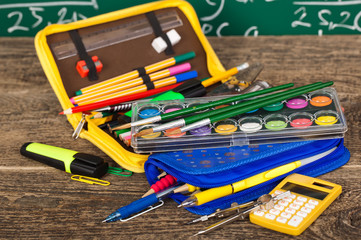 Back to school - blackboard with pencil-box and school equipment on table