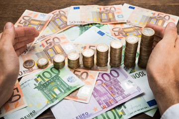 Businessman Protecting Coins And Banknotes