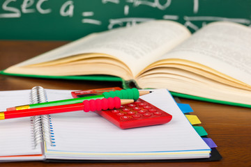 Back to school - blackboard with pencil-box and school equipment on table