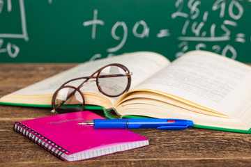 Back to school - blackboard with pencil-box and school equipment on table