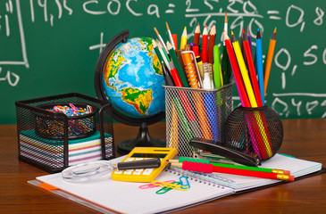 Back to school - blackboard with pencil-box and school equipment on table
