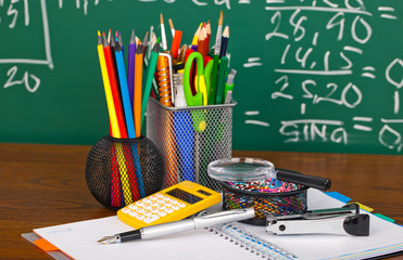 Back to school - blackboard with pencil-box and school equipment on table