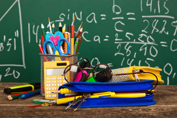 Back to school - blackboard with pencil-box and school equipment on table