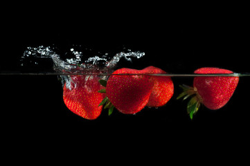 Strawberries splashing into water