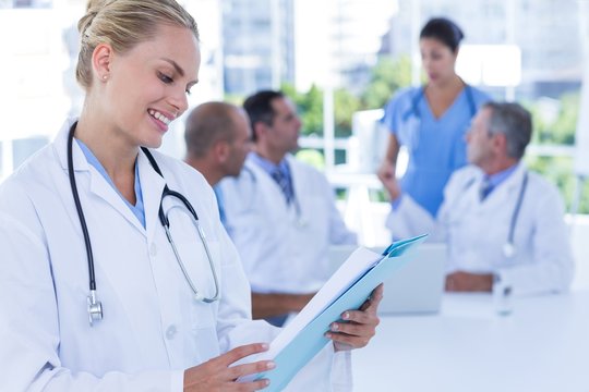Smiling female doctor looking at clipboard