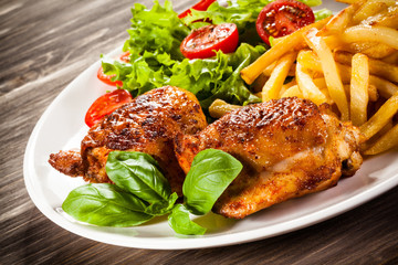 Grilled chicken legs with chips and vegetables 