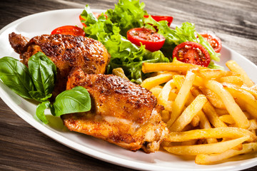 Grilled chicken legs with chips and vegetables 