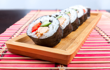 Sushi on a wooden platter and bamboo mat