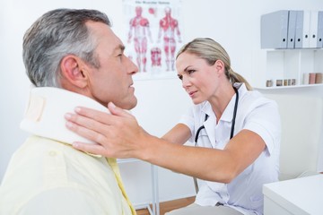 Obraz premium Doctor examining patient wearing neck brace