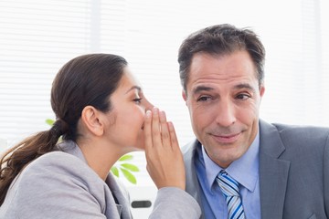 Businesswoman whispering something to her colleague