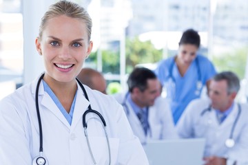 Smiling female doctor looking at camera while her colleagues wor
