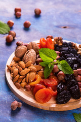 Healthy concept: assortment of dry fruits and nuts on blue rustic background. Selective focus