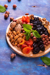 Healthy concept: assortment of dry fruits and nuts on blue rustic background. Selective focus