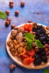 Healthy concept: assortment of dry fruits and nuts on blue rustic background. Selective focus